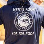 Roofer wearing a navy hoodie with 'Need a Roof?' and a Florida Quality Roofing logo; phone number 305-306-ROOF visible.