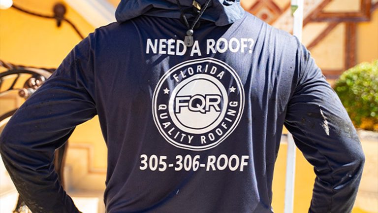 Roofer wearing a navy hoodie with 'Need a Roof?' and a Florida Quality Roofing logo; phone number 305-306-ROOF visible.