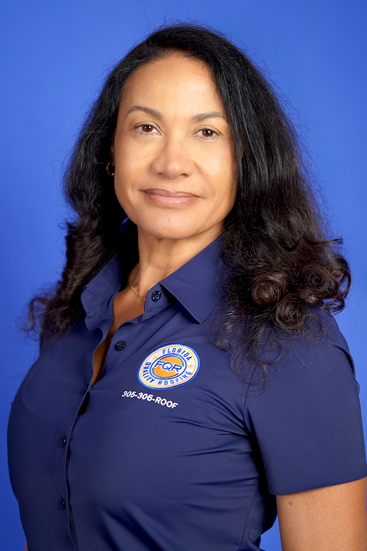 Professional portrait of a woman with dark hair wearing a blue polo shirt with a roofing company logo against a blue background.