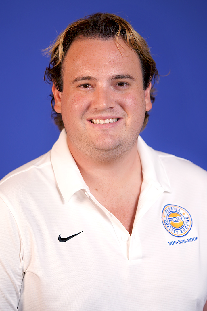 Head-and-shoulders portrait of a smiling man with light brown hair, wearing a white polo with a circular logo on the chest, against a blue background.